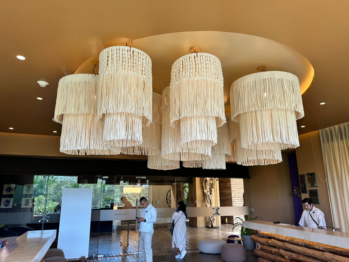 Conjunto de lámparas textiles con flecos crudos sobre la recepción de Xcaret Arte.