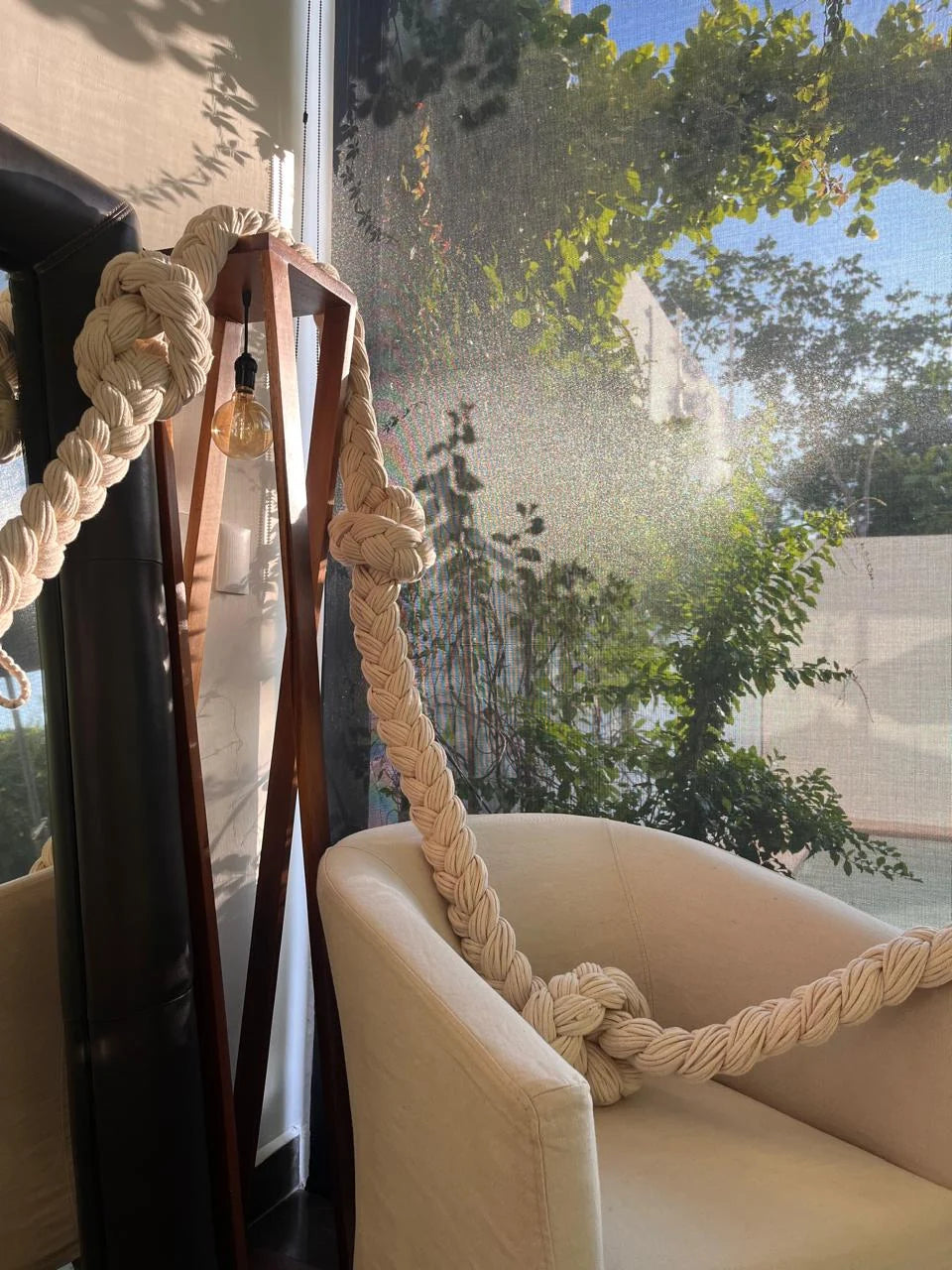 The end of the braided composition beside an armchair and a window overlooking greenery.