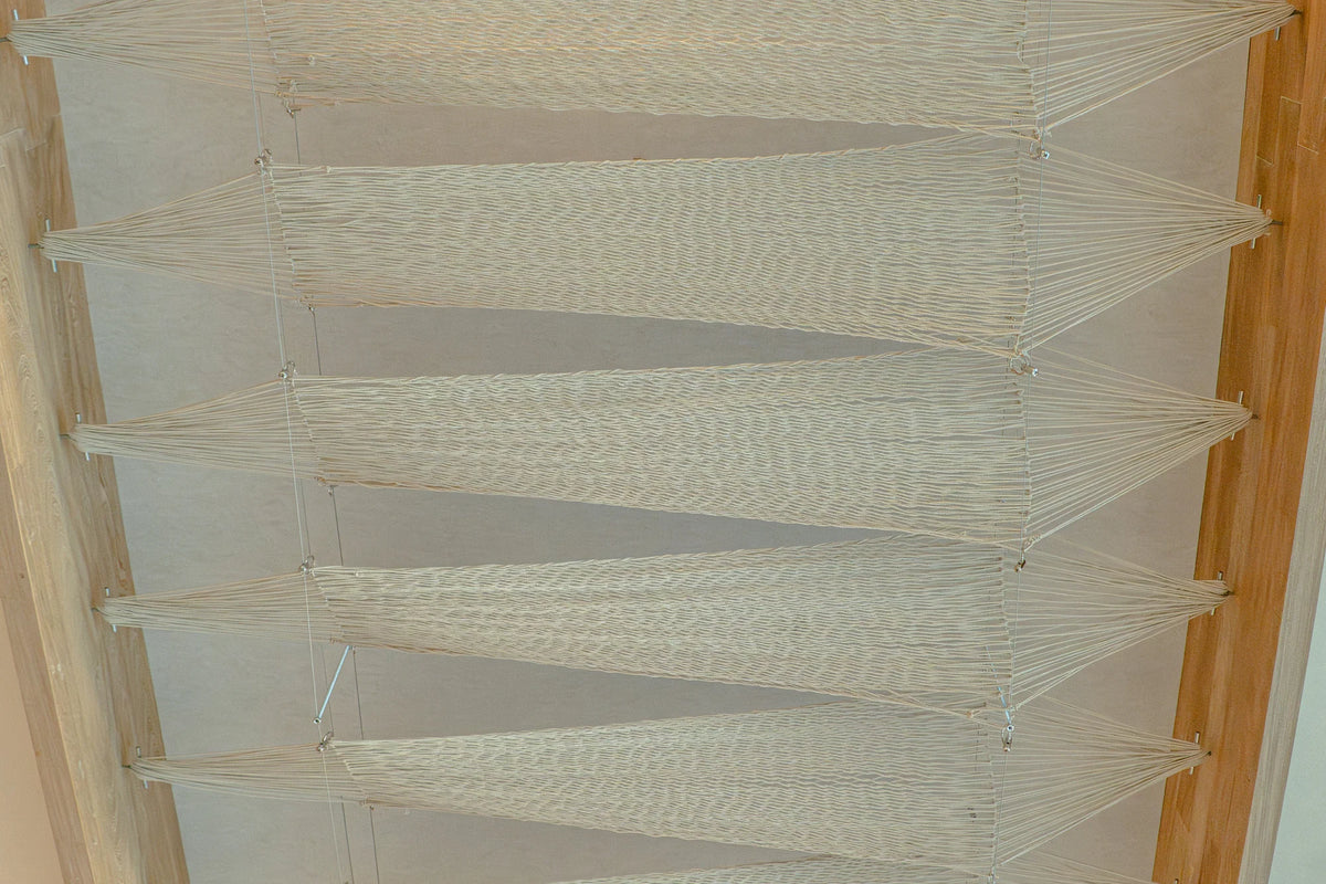 View from below of woven panels stretched between the timber edges of the ceiling.