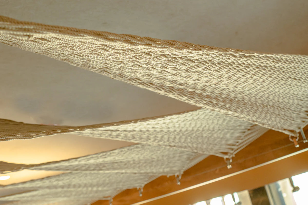 Close view of the pale ceiling weave, with warm light between the woven surfaces.