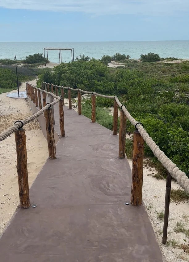 A path towards the beach with wooden posts and a braided rope handrail.