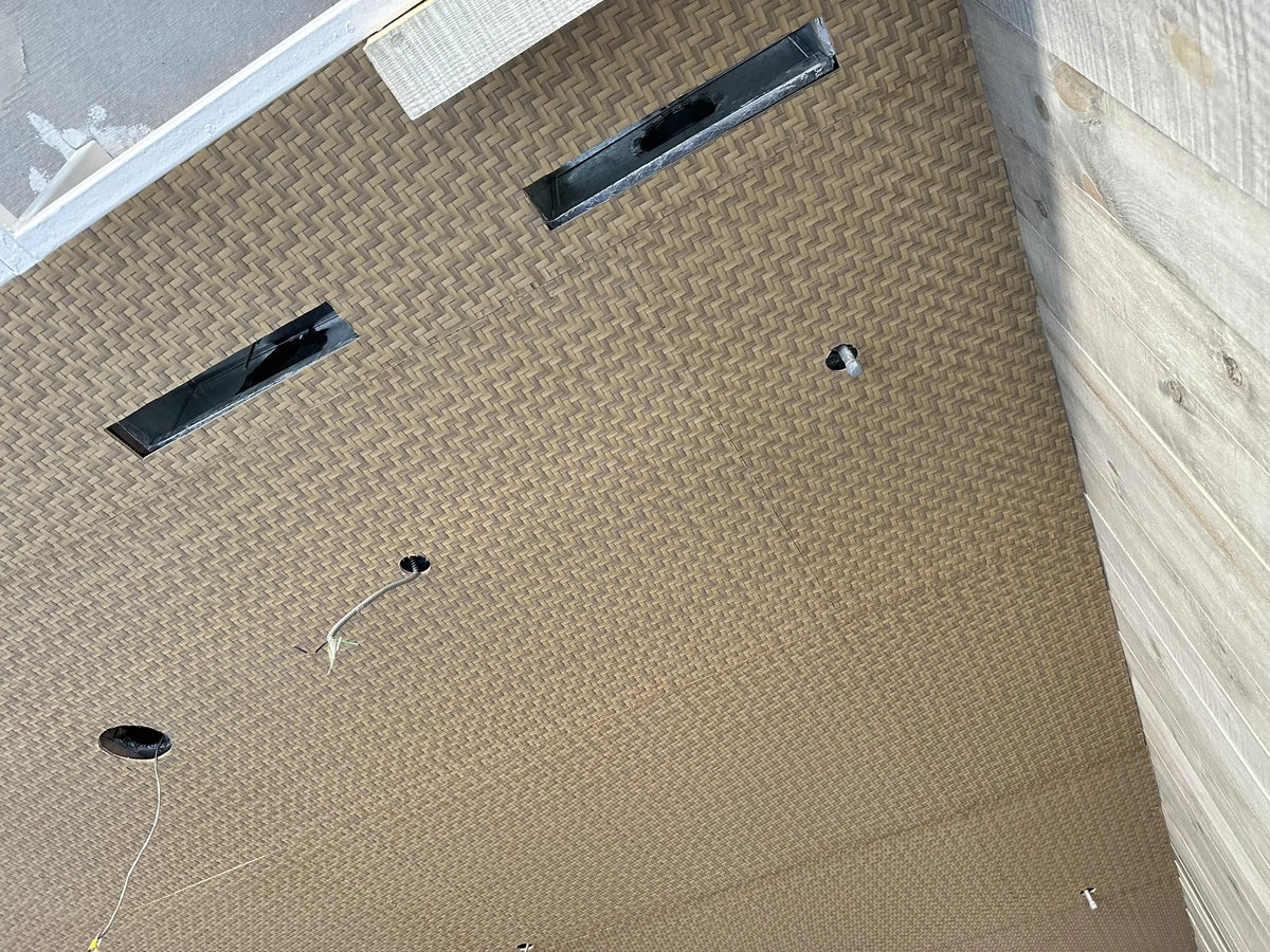 Close-up of the ceiling weave beside the wall, with openings for the building services.