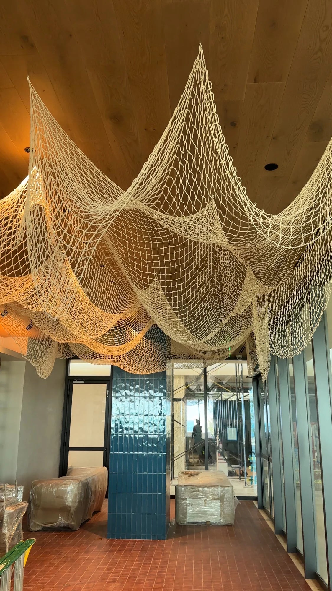 Draped decorative net beside a blue column and an entrance, during the interior fit-out.