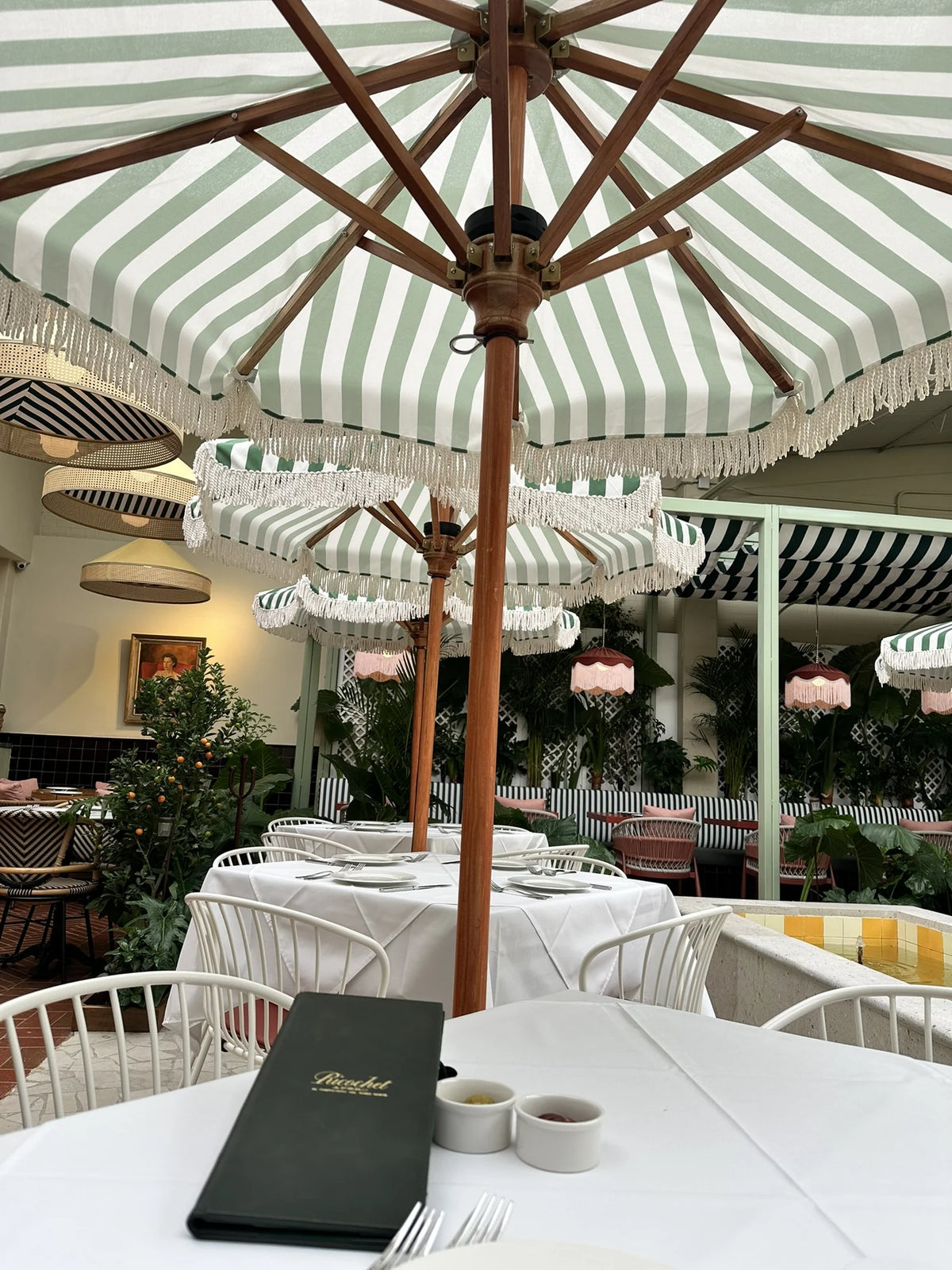 Green and white striped parasols with pale fringe above the tables at Ricochet.