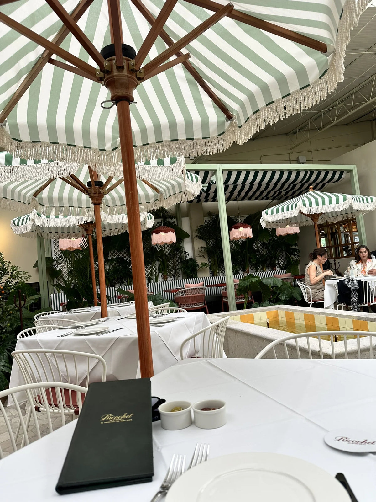 Side view of the fringed parasols, tables and yellow tiled fountain at Ricochet.