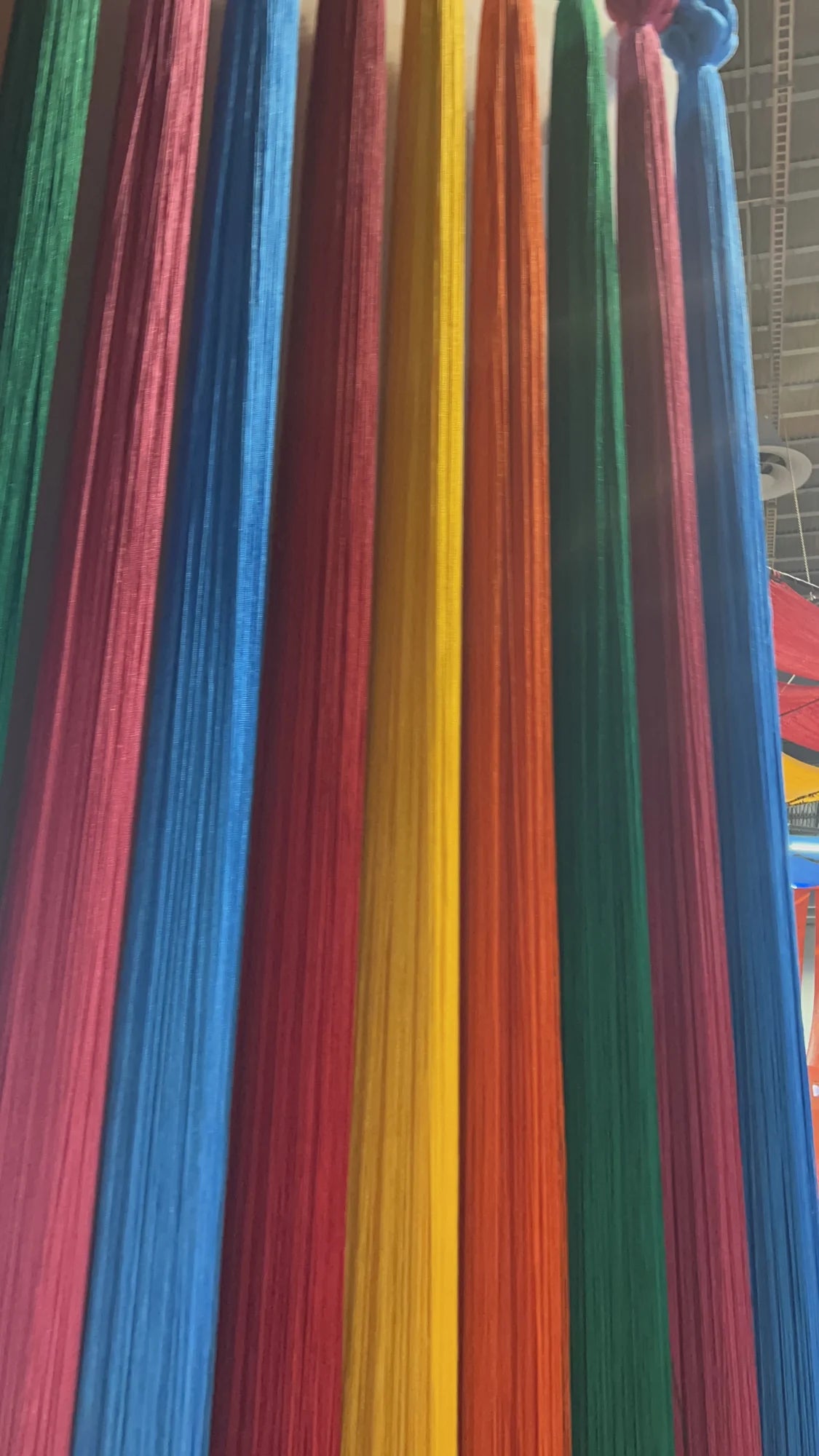 Detail of vertical threads in green, pink, blue, yellow and orange, with knots at the top.