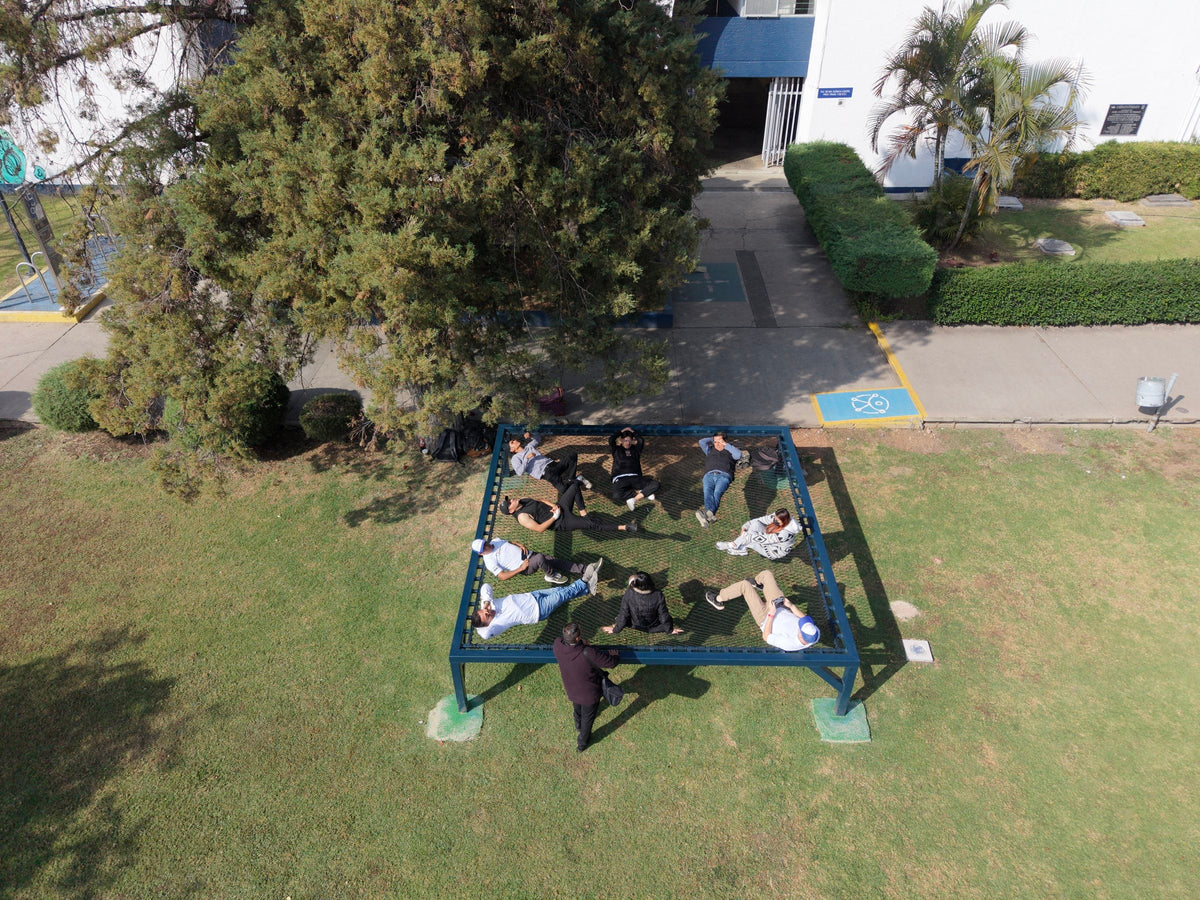 Vue aérienne d’un filet de détente sur cadre bleu accueillant plusieurs personnes dans un jardin du Michoacán.