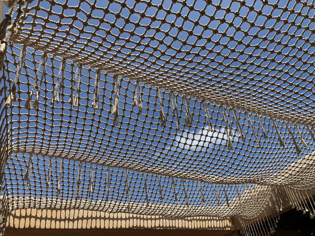 Détail des nœuds et des franges d’une pergola tissée sur fond de ciel bleu à Playa del Carmen.