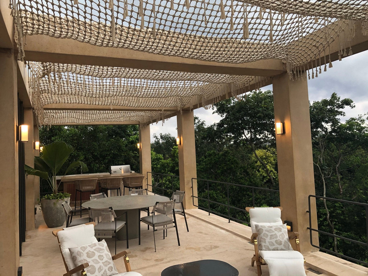 Pergola habillée d’un tissage au-dessus d’une terrasse avec espace repas et végétation à Playa del Carmen.
