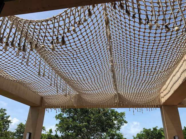 Vue de dessous d’une couverture tissée à franges au-dessus d’une terrasse à Playa del Carmen.