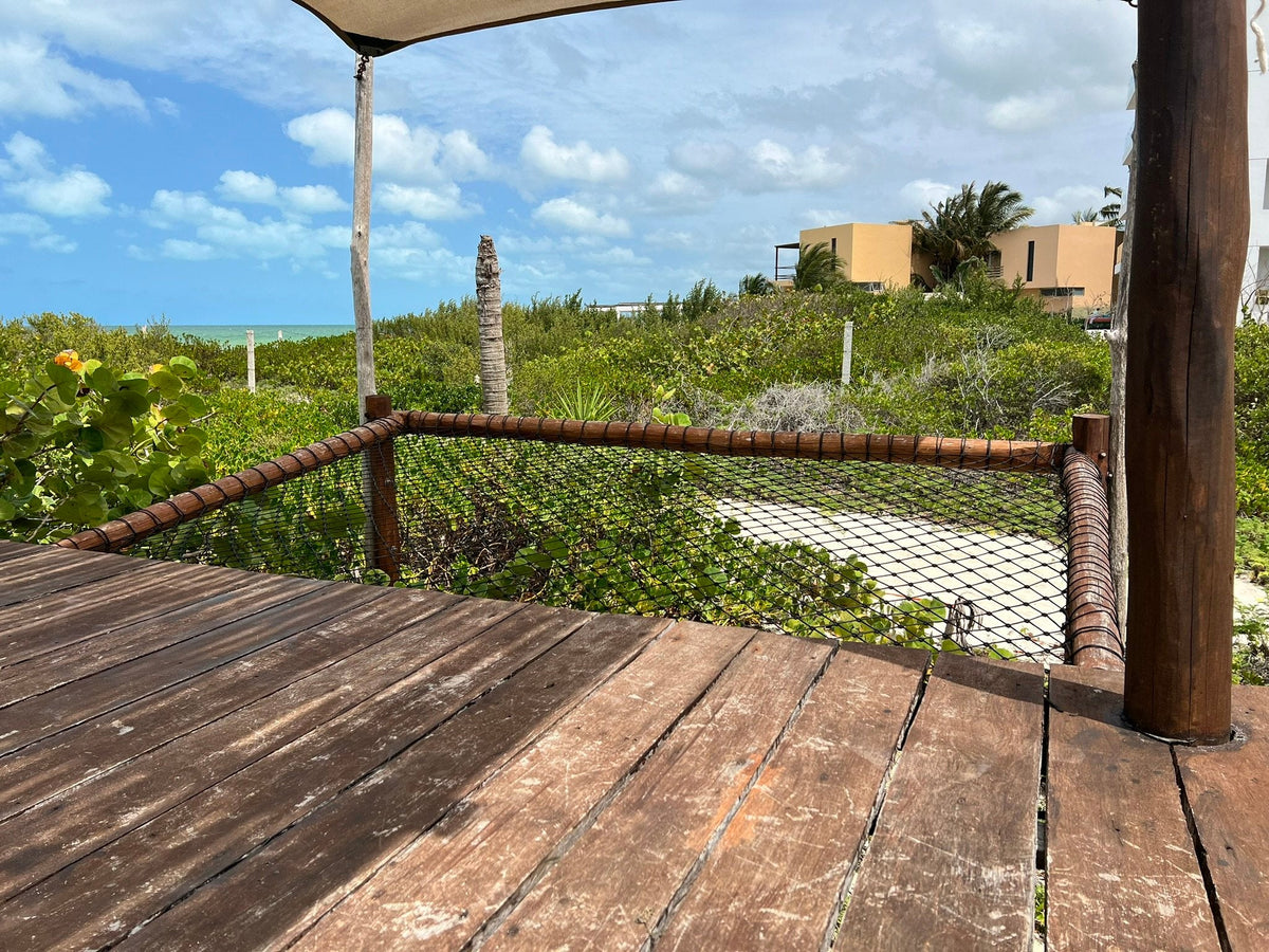 Filet noir intégré à une terrasse en bois au milieu de la végétation côtière à Telchac, au Yucatán.