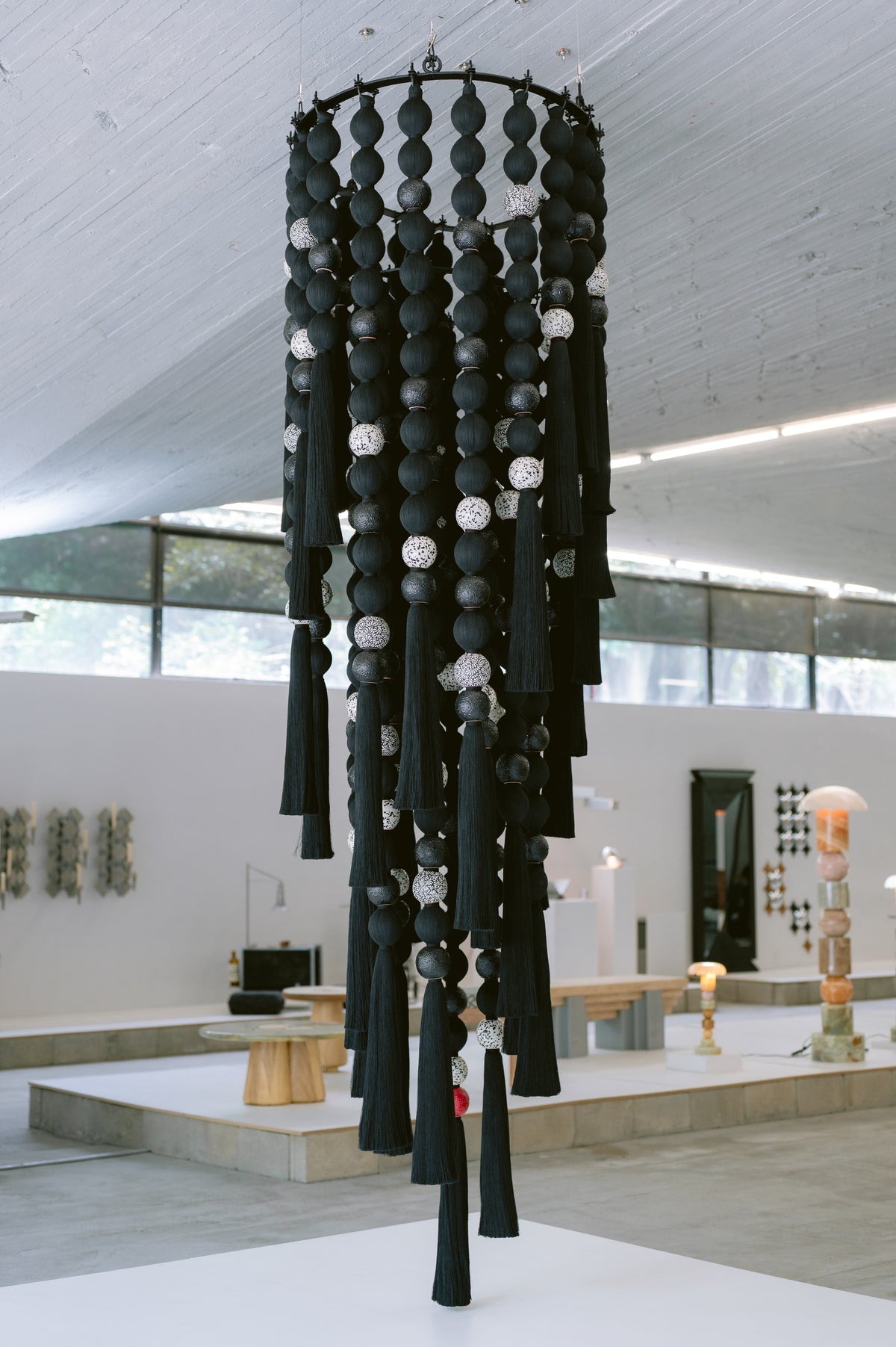 Escultura textil FILAMENTO suspendida, con volúmenes negros, cerámica en blanco y negro y flecos largos.