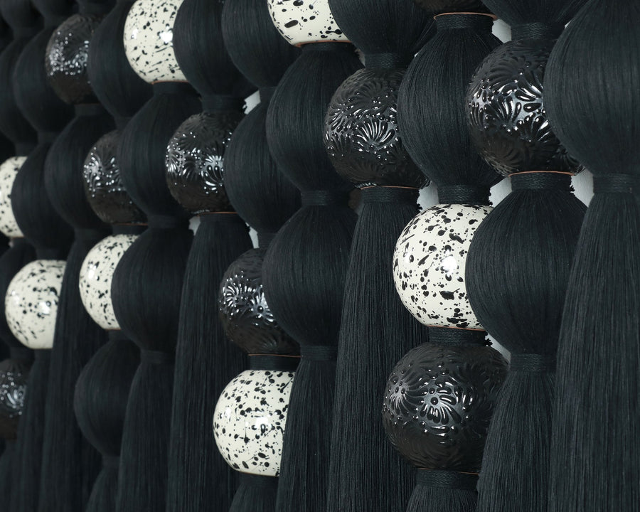 Detalle de las piezas cerámicas decoradas y el hilo negro del Tapiz Filamento.